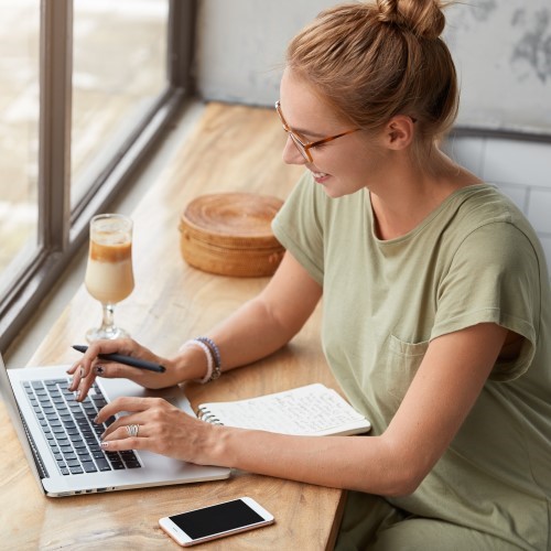 rfolgreiche Freiberuflerin mit Haarknoten bietet Online-Marketing-Dienstleistungen an, betreut Websites und soziale Netzwerke, bewirbt bestimmte Produkte und arbeitet in ihrer Freizeit in einem Café mit Smoothies.